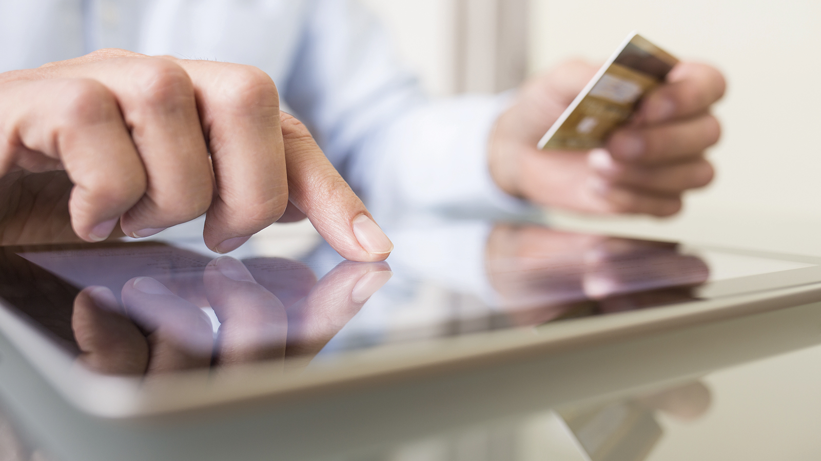 Man holding credit card and typing on a tablet