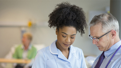 Doctor and nurse discussing over digital tablet in ward at hospital