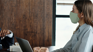 Young business woman wearing face mask working on computer 